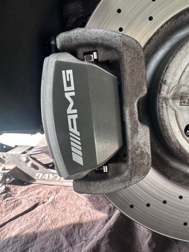 Close-up of AMG-branded stock brake calipers before custom caliper painting on a Mercedes AMG GT53 in Lawrenceville, GA.